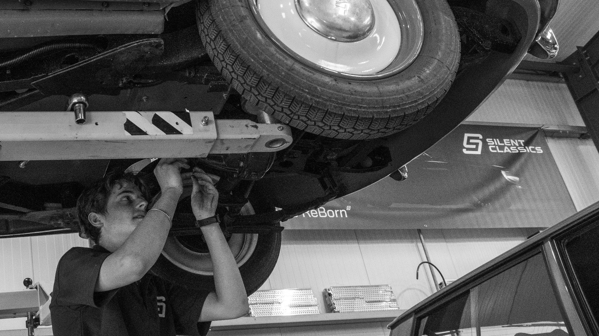 Silent Classics engineer servicing a Fiat 500e on a workshop lift